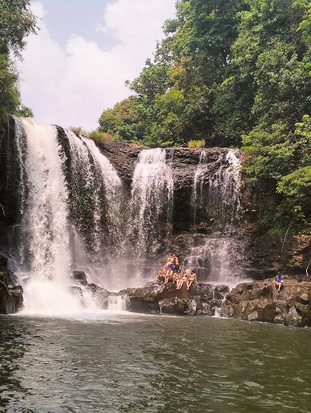 Adventure group of visitors posing at pristine waterfall during guided trek from Shared Happy Farm