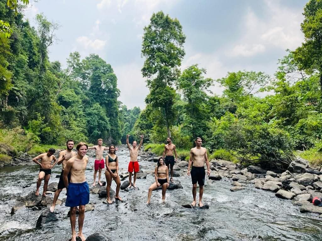 Visitors on guided waterfall trekking adventure through pristine jungle paths near the farm